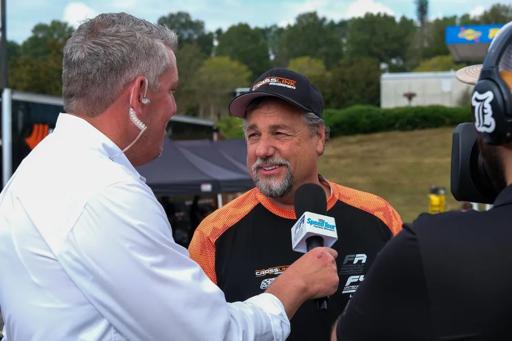 Gill Kaszuba giving a trackside interview in Crosslink Motorsports team wear